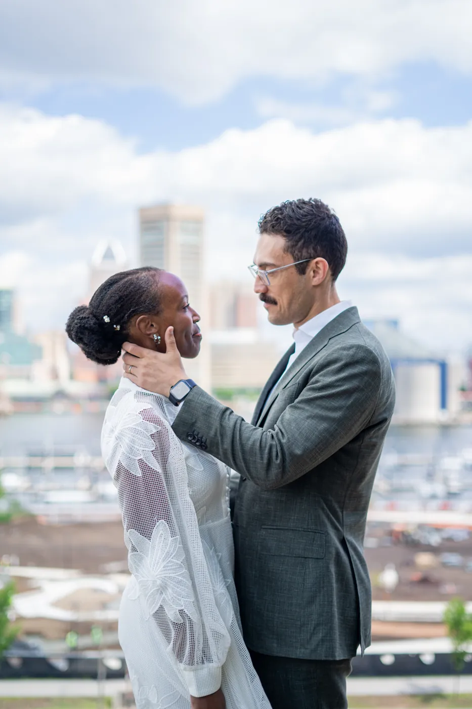 Engaged couple embracing with a city skyline behind them