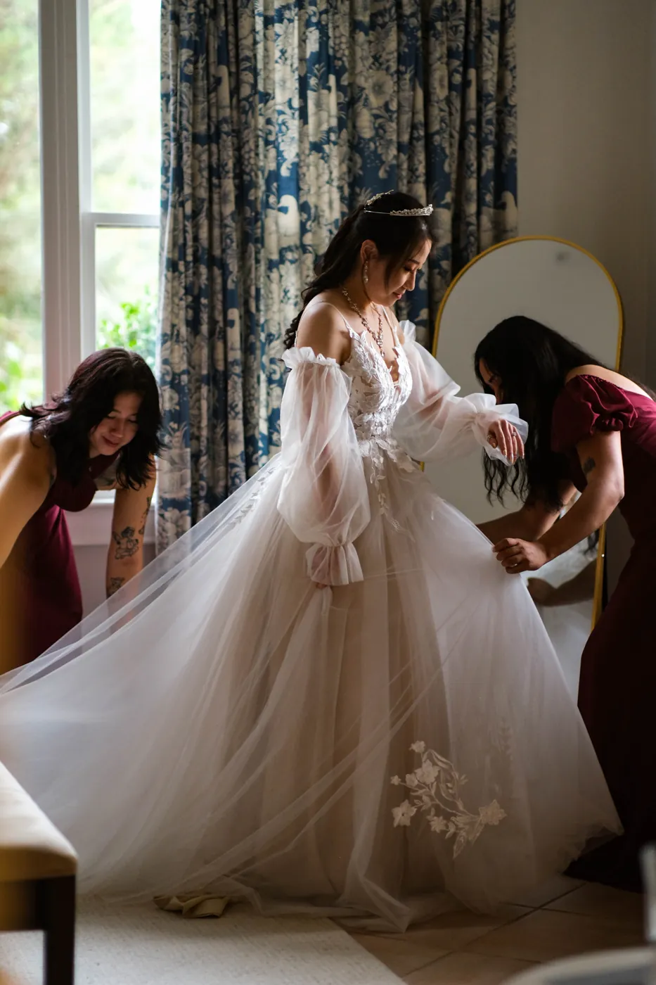 Bride having her wedding dress adjusted by bridesmaids