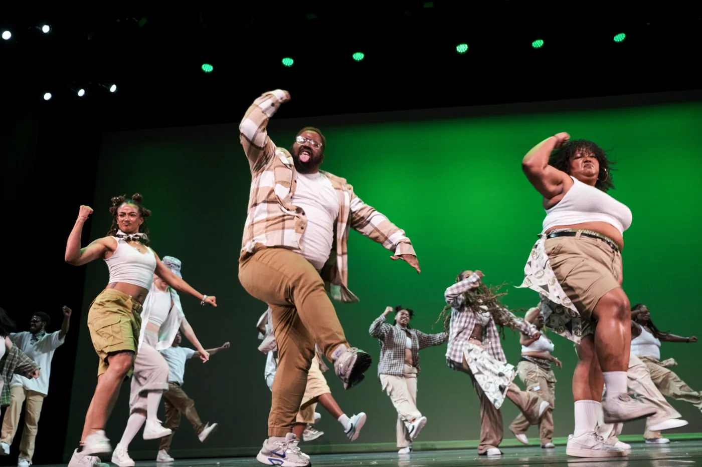 Dancer mid-performance on stage with green lighting