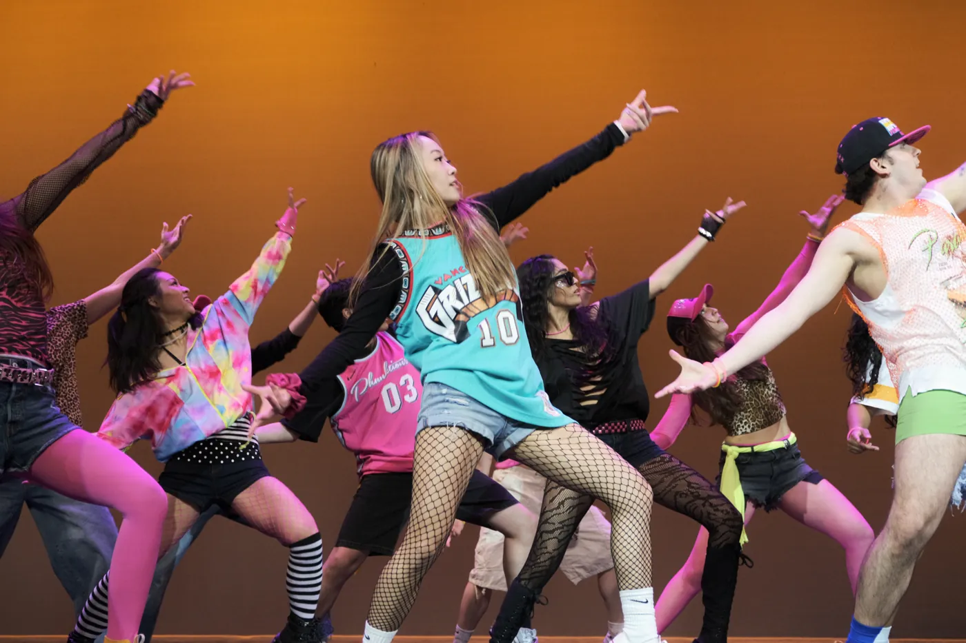 Dancers mid-performance on stage with orange lighting