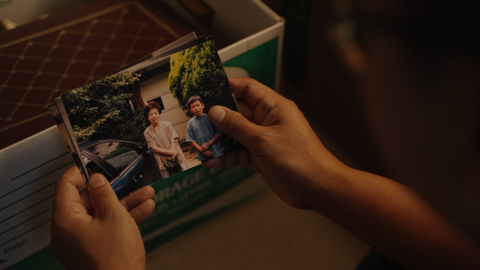 Hands holding an old family photograph from a storage box