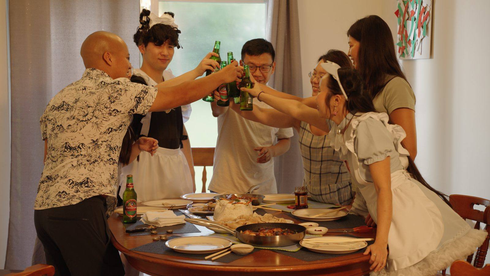 Friends toasting with Tsingtao beers around the dinner table