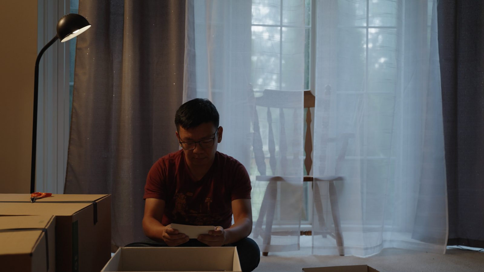 Siwei sitting quietly by a window, reading a letter